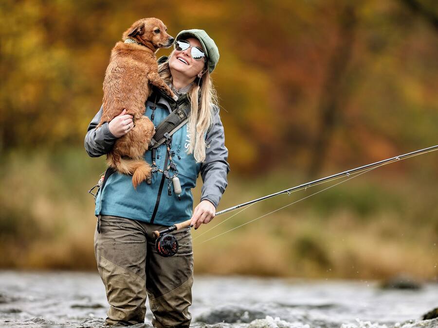 A person holding a dog in a natural outdoor setting.