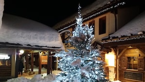 A snow-covered Christmas tree with lights in front of a building with a sign that reads "PIZZA & CAFE". - BELLE PLAGNE, cosy 2 rooms, skis on / cleaning and covered parking included !!! (La Plagne Tarentaise)