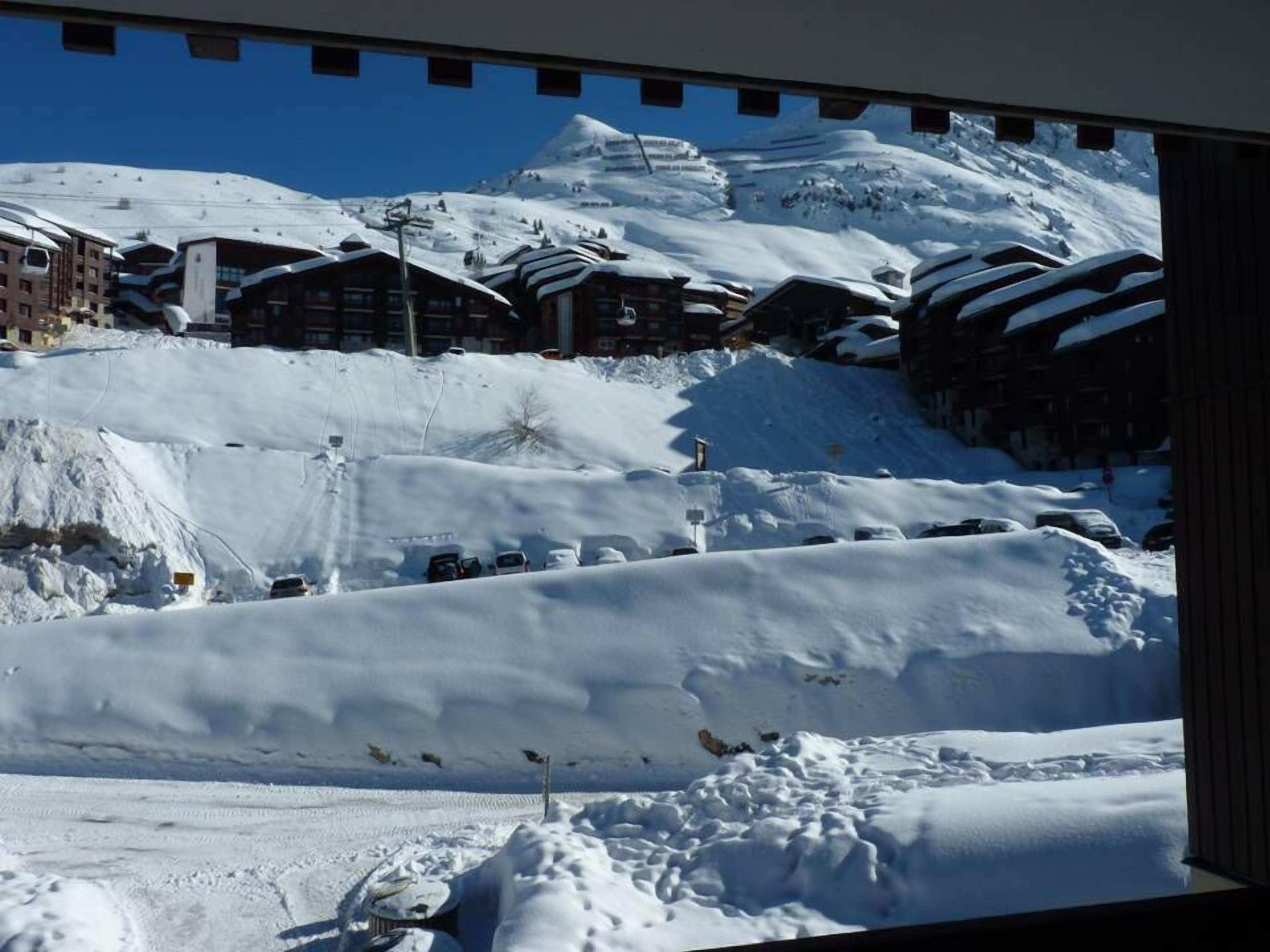 A snow-covered ski resort with buildings and a mountain in the background.
