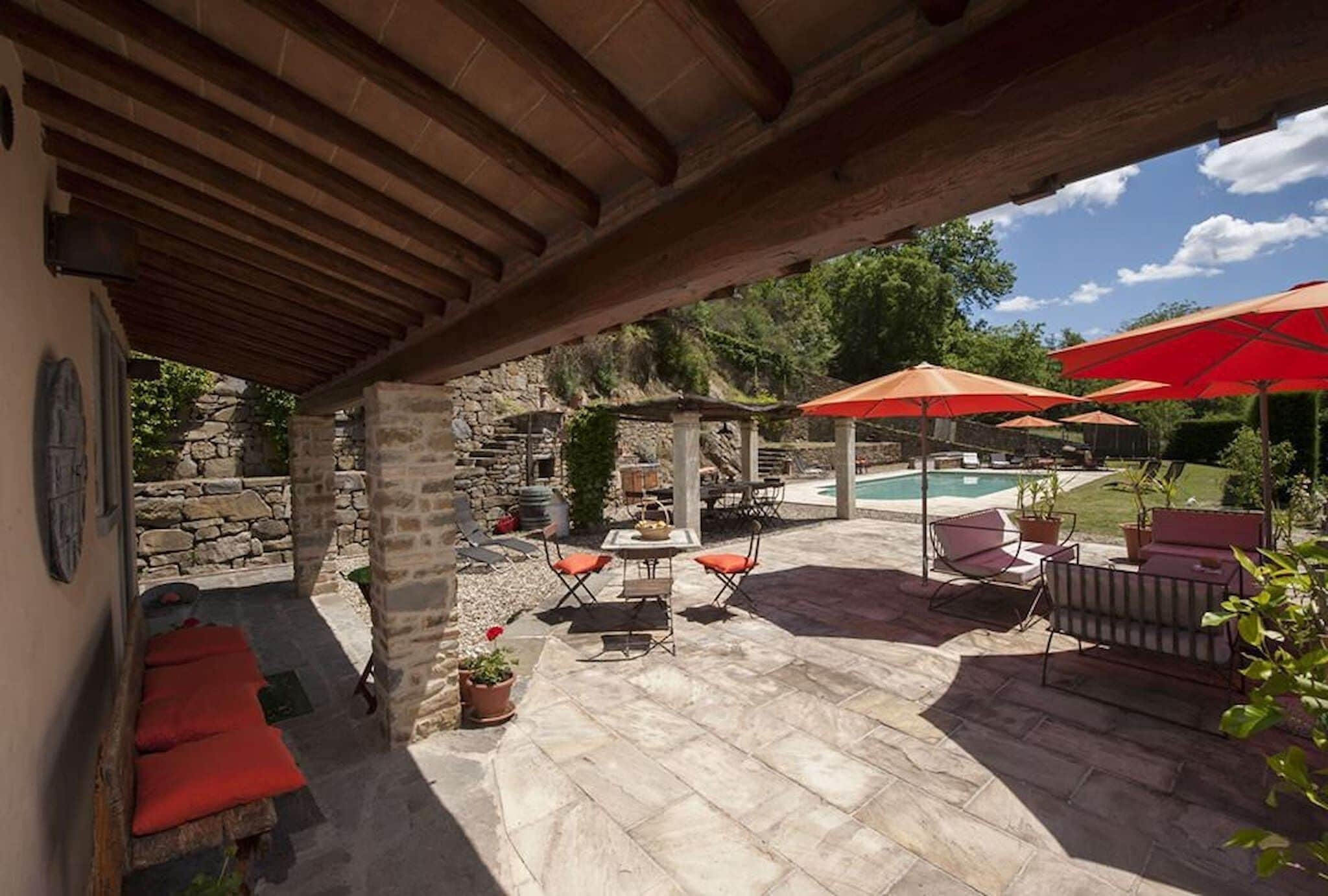 Ein Außenbereich mit Terrassenfliesen, einem Pool und roten Sonnenschirmen.