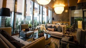 Un hall d’hôtel moderne, doté de grandes fenêtres, de sièges confortables et d’un éclairage décoratif.
