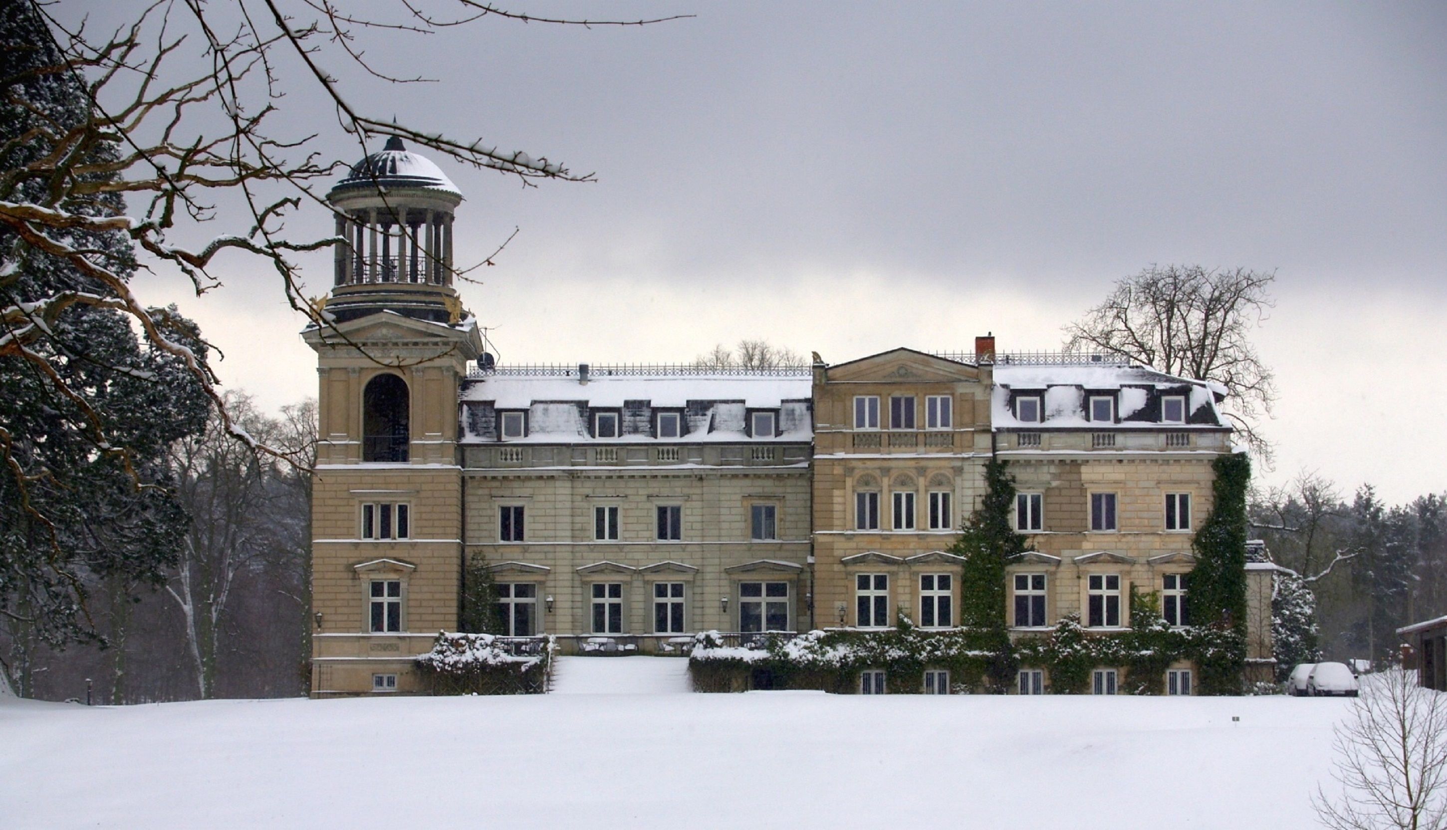 A large, historic building with a prominent tower and multiple windows, surrounded by snow.