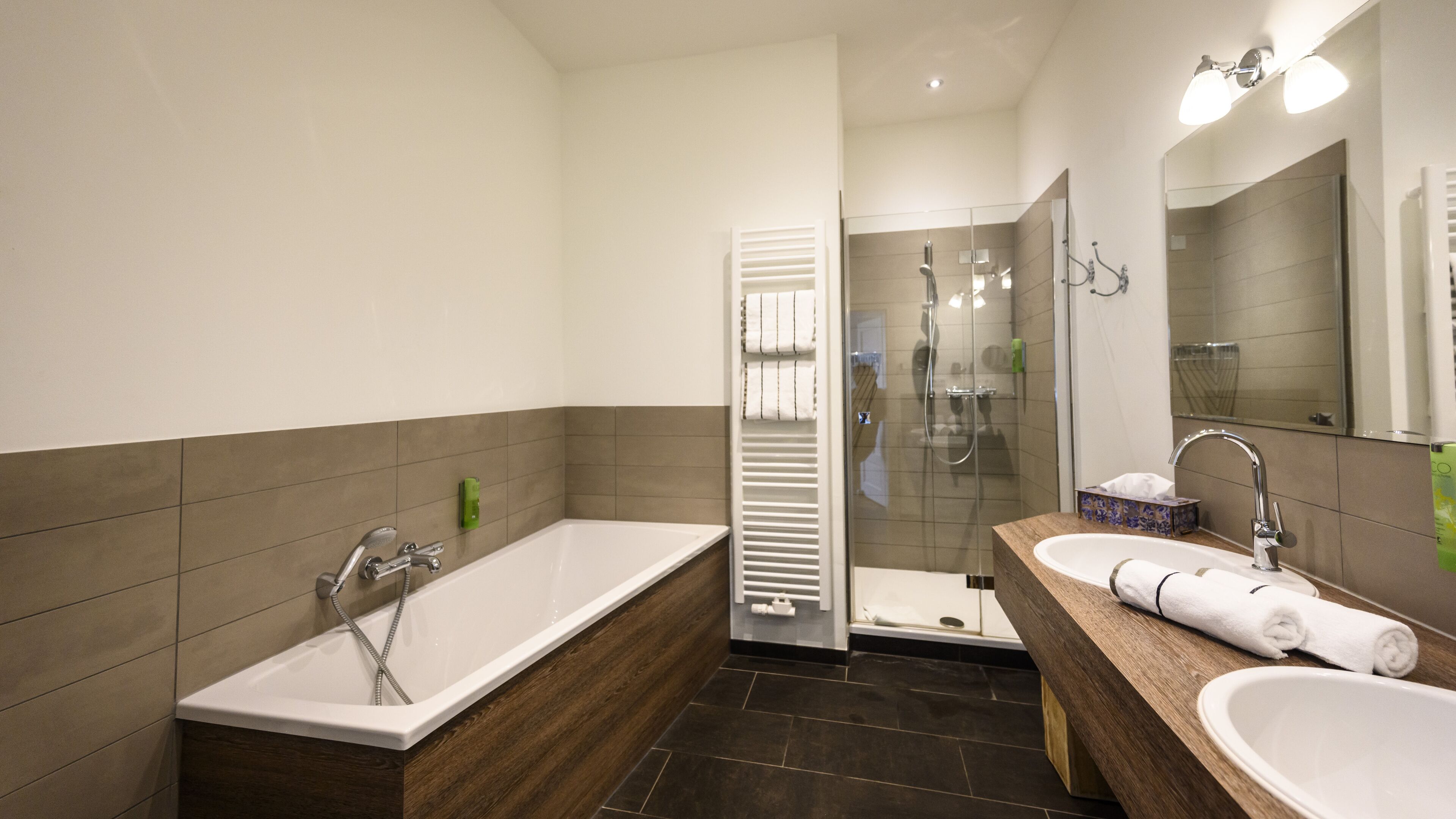 Een moderne badkamer met een bad, douche en wastafel.