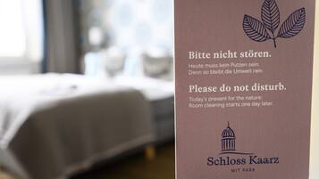 A sign in a hotel room with text in German and English advising guests not to disturb as room cleaning starts the next day. The sign features a leaf and a building icon.
