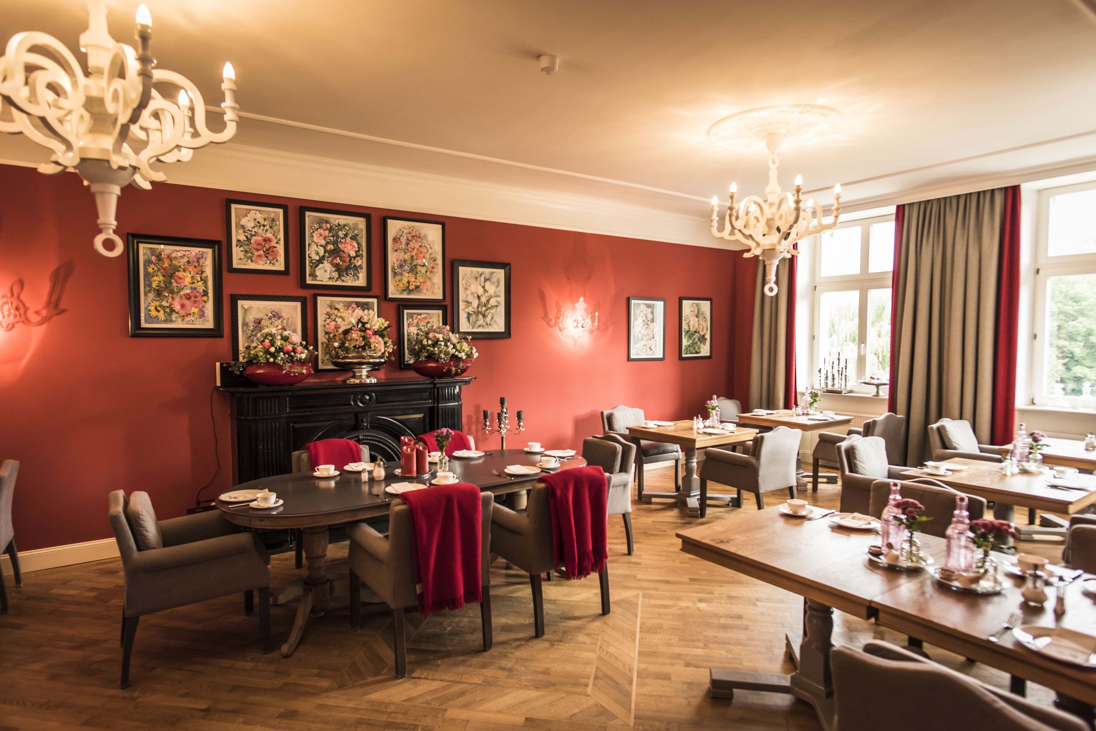 Comedor con varias mesas y sillas, chimenea decorada con motivos florales y obras de arte en las paredes.