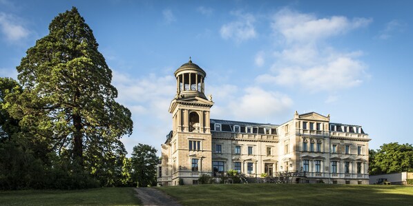A large, historic building with a prominent tower and multiple windows. - Schloss mit Park Kaarz (Weitendorf)
