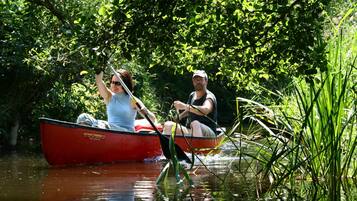 Two people in a red boat on a calm river surrounded by lush greenery.