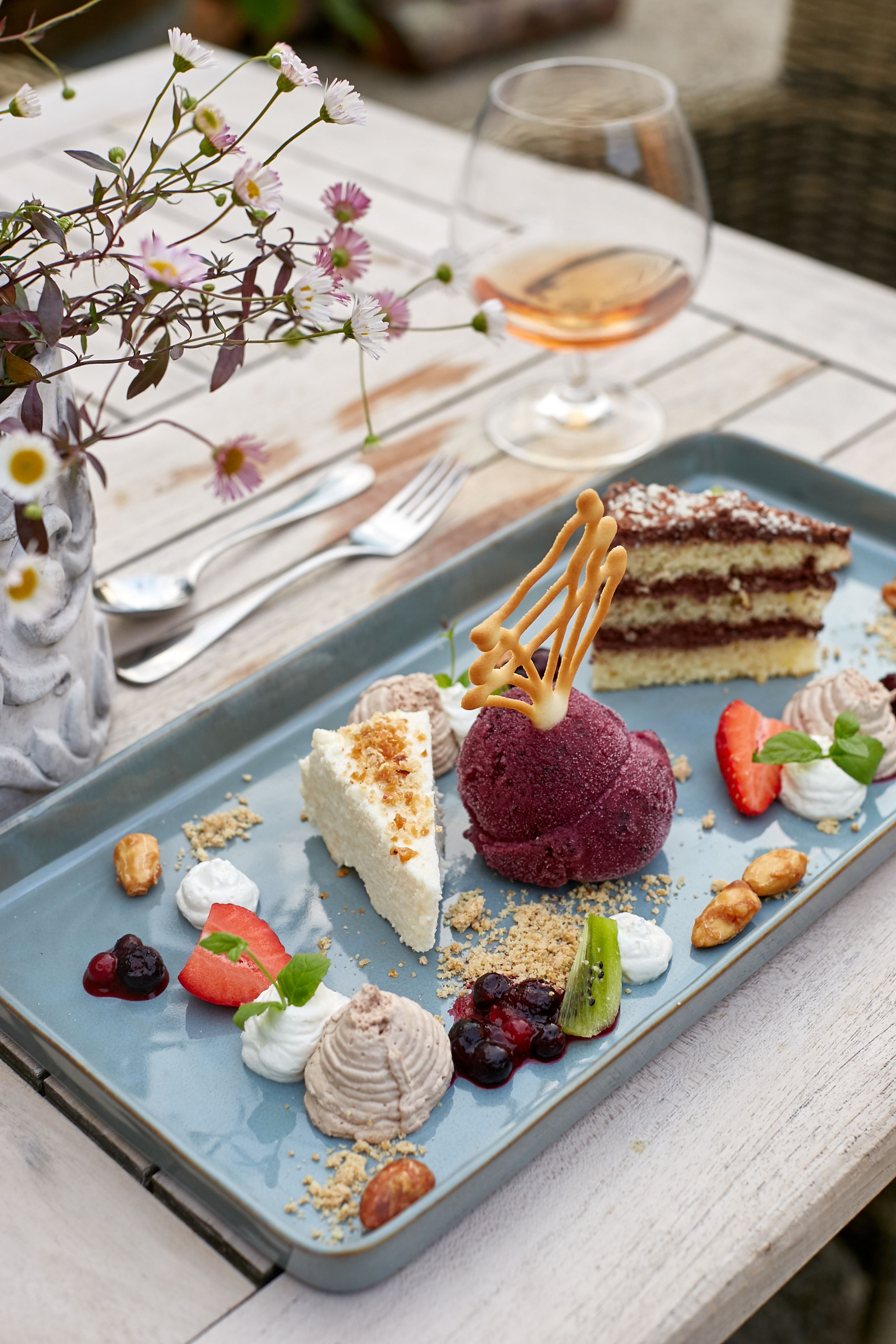 A dessert plate with various sweets and a glass of wine on a table.