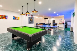 Una sala de billar con mesa de billar, mesa de snooker y dardos.