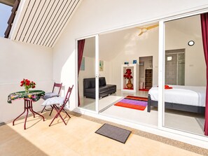 Una habitación moderna con cama, sofá, mesa con sillas y un cerrojo corredizo que da a otra habitación.