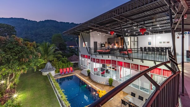 Un hotel moderno con piscina, asientos al aire libre y vistas a las colinas circundantes.