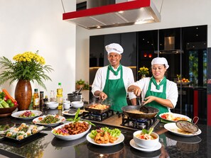 A modern kitchen with chefs preparing food, a variety of dishes on the counter, and a decorative plant. - Luxury villa mountain view 10BR /Private chef available (Soi Themrat Chalong Muang)