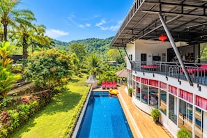Un hotel moderno con piscina, exuberante vegetación y vistas a un paisaje montañoso.