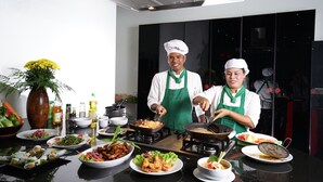 Una cocina con chefs preparando comida, varios platos en la encimera y equipo de cocina.