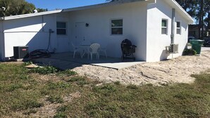 A single-story house with a patio, a grill, and a small table with chairs.