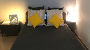 Un dormitorio con una cama grande, dos mesitas de noche, una lámpara de pared y un cuadro enmarcado sobre la cama.