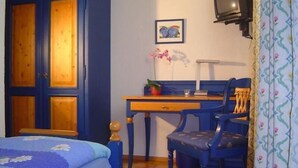 A bedroom with a bed, a desk, a chair, a television, and a wardrobe. - Landhotel Mühlberg (Moessingen)