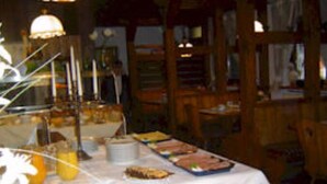 A dining area with a table set for breakfast, including plates, bowls, and a fruit bowl. - Landhotel Mühlberg (Moessingen)