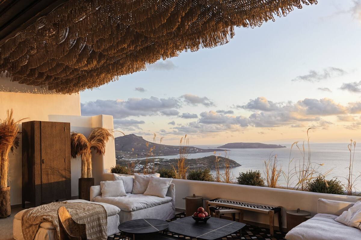 A cozy outdoor seating area with a view of the sea and a distant island.