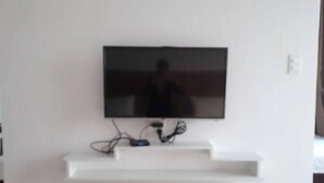 Un televisor de pantalla plana montado en una pared blanca, con un sistema de organización de cables debajo.