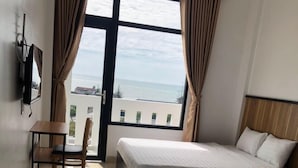 Habitación de hotel con dos camas, una silla, un televisor y vista al mar.
