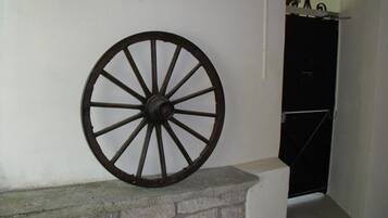 Una gran rueda de madera montada sobre un borde de piedra junto a una pared blanca.