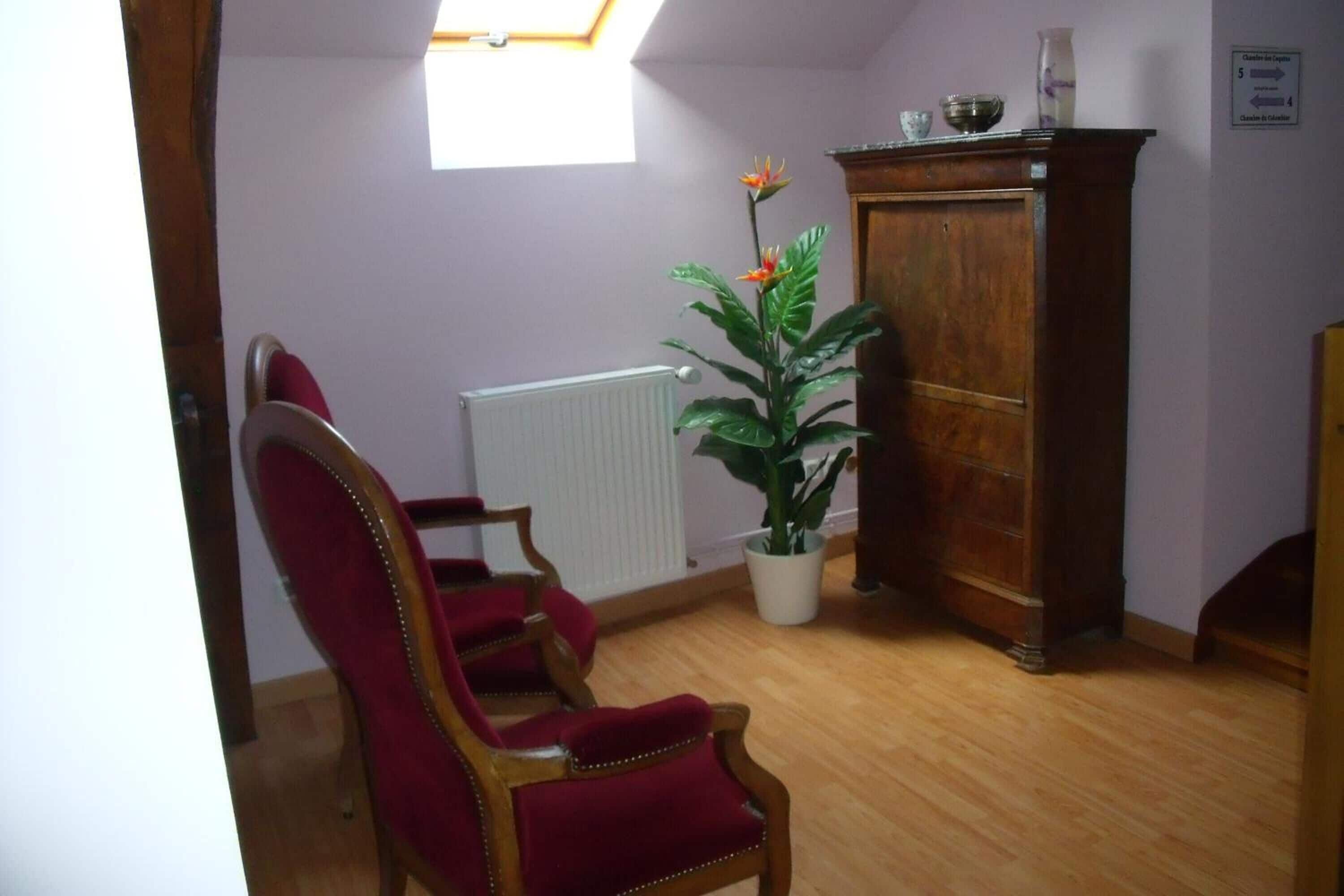 Ein Zimmer mit einem Holzhöhenheizkörper, einem roten Sessel, einem Holzschrank und einem Blumentopf.