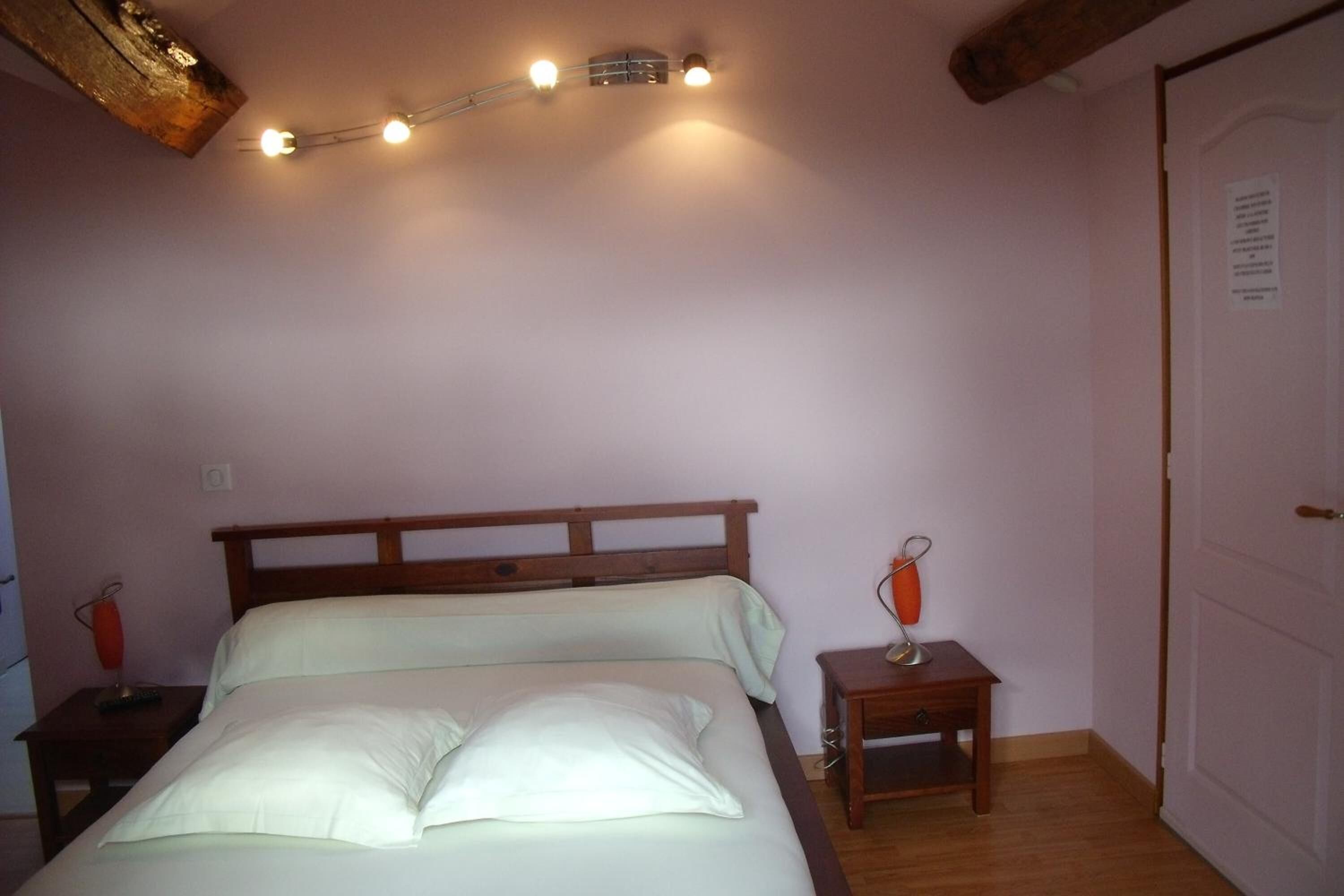 A bedroom with a wooden bed, bedside tables, and a ceiling light fixture.