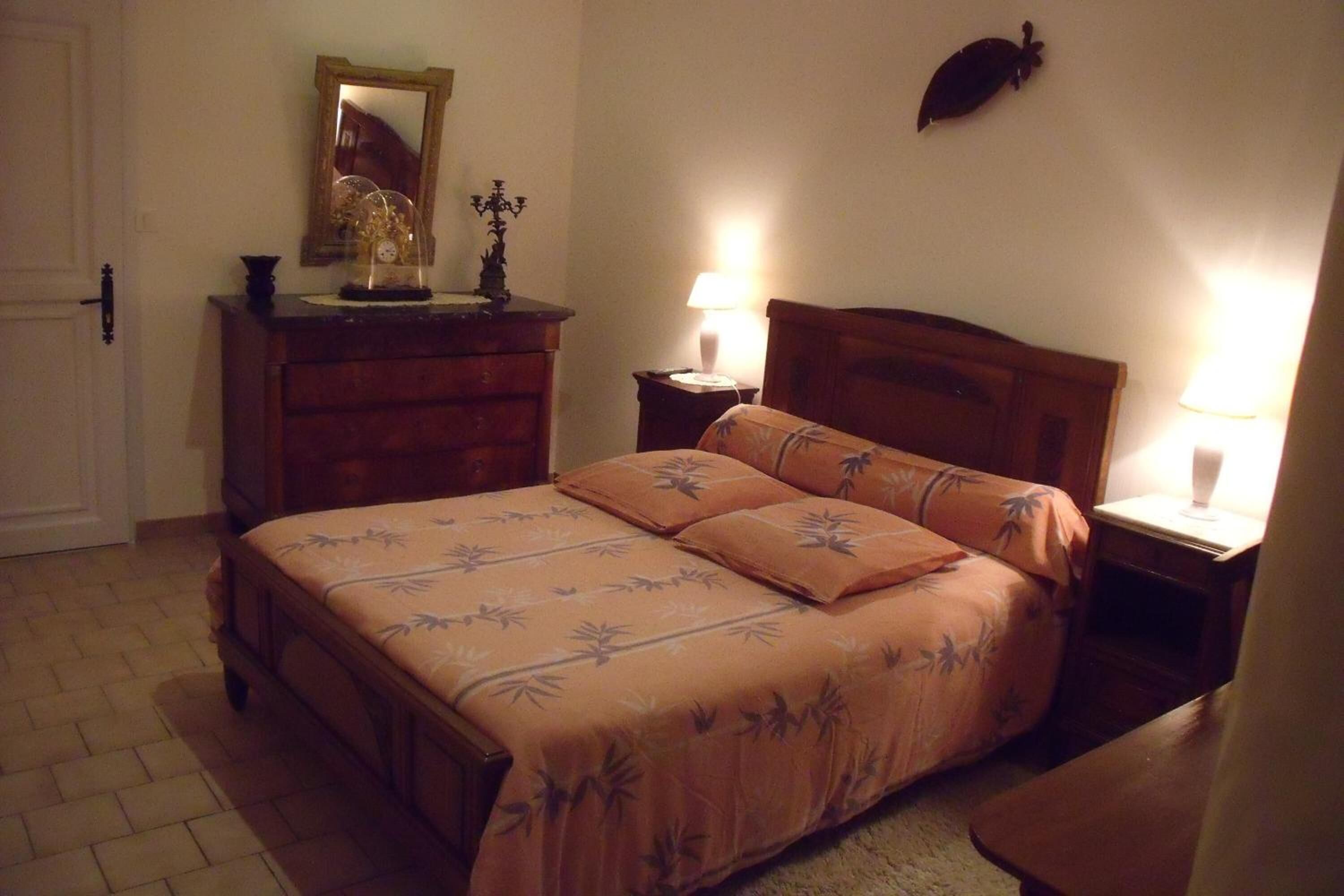 A bedroom with a bed, dresser, nightstands, and lamps.