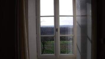 A room with a large window offering a view of a grassy landscape and trees.