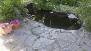 A stone-paved garden with a pond, surrounded by greenery and two flower pots. - 2 bedroom Suite at the historic Port Albert Inn in beautiful Port Albert, Ontario! (Ashfield Colborne Wawanosh)