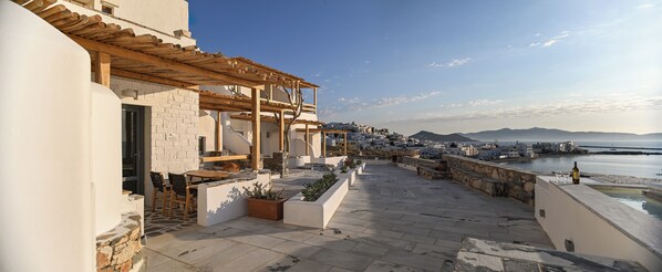 A rooftop terrace with a pergola, seating area, and a view of the sea and town. - Iliada Suites - Adults only (Naxos)