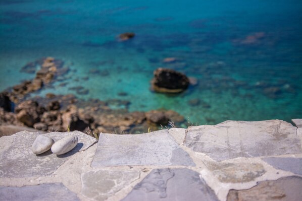A stone ledge with a view of clear blue water and rocks.