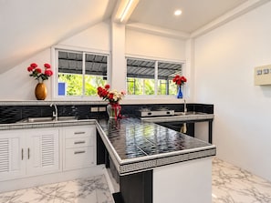 Cozinha moderna com painel de azulejos preta e branca, armários brancos e uma ilha central com bancada preta.