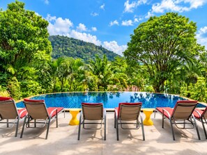 Une piscine dotée de chaises longues et offrant une vue sur un paysage verdoyant.