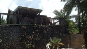 A swimming pool with a stone wall and a wooden deck. - Les Vanilliers (Saint-Joseph)