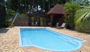 Una piscina al aire libre, sillones reclinables de piscina
