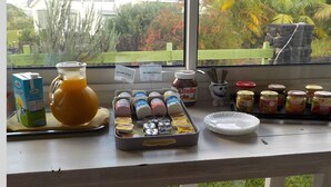 A breakfast setup with a pitcher of orange juice, condiments, and a tray of pastries. - Les Vanilliers (Saint-Joseph)
