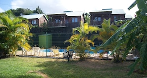 Un espace extérieur clos, doté d’une piscine, de palmiers et d’un bâtiment avec un balcon.