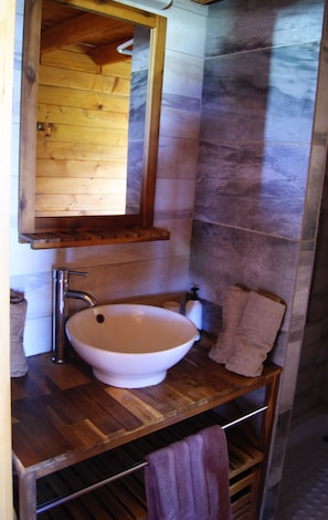 Une salle de bain avec un meuble-lavabo en bois, un lavabo blanc, un miroir au-dessus du lavabo et une serviette suspendue à un porte-serviettes.