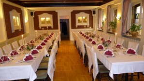 A long dining hall with tables set for a formal event, featuring white tablecloths and red centerpieces. - Hotel Die Post in Bürgel GmbH (Offenbach am Main)