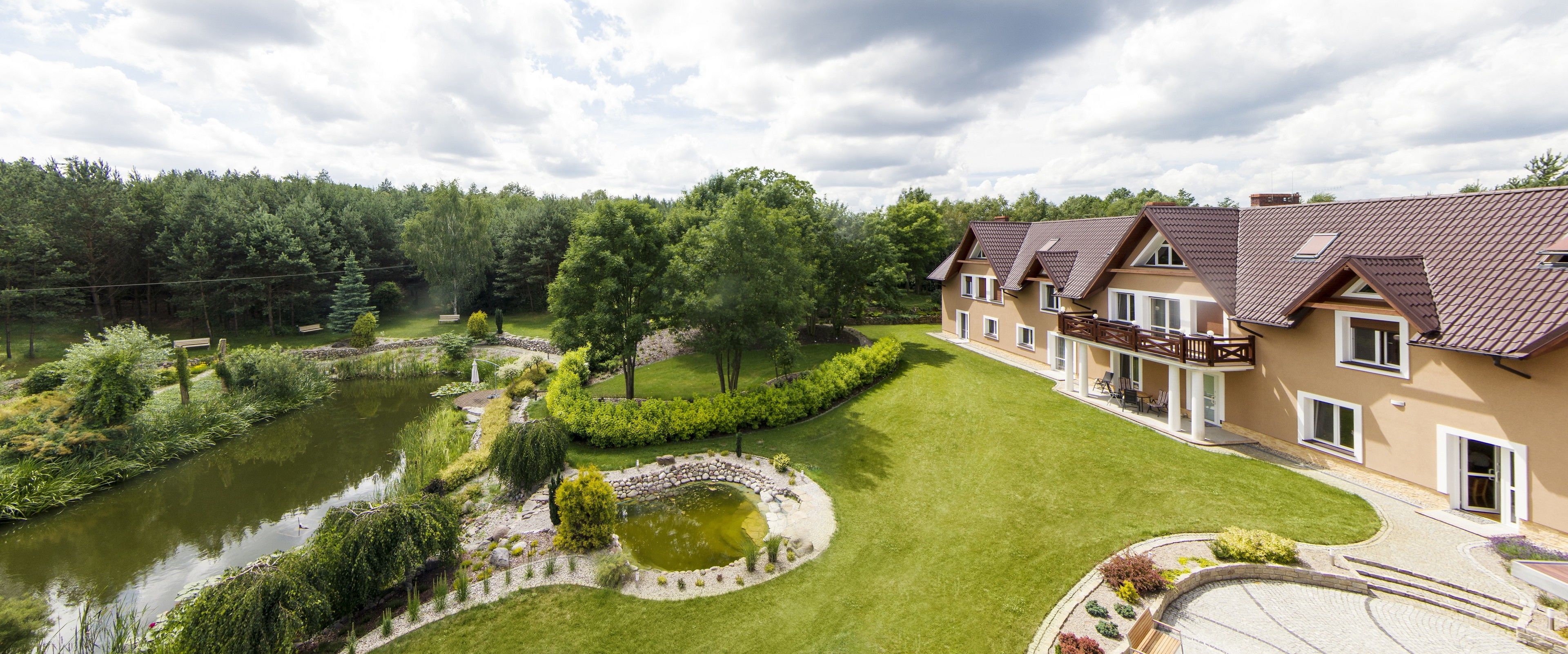 A residential area with a pond, a well-maintained lawn, and a row of houses with a balcony.