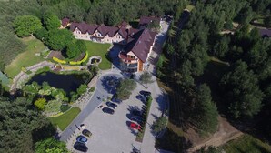 An aerial view of a residential area with a large house, a parking lot, and a lake.