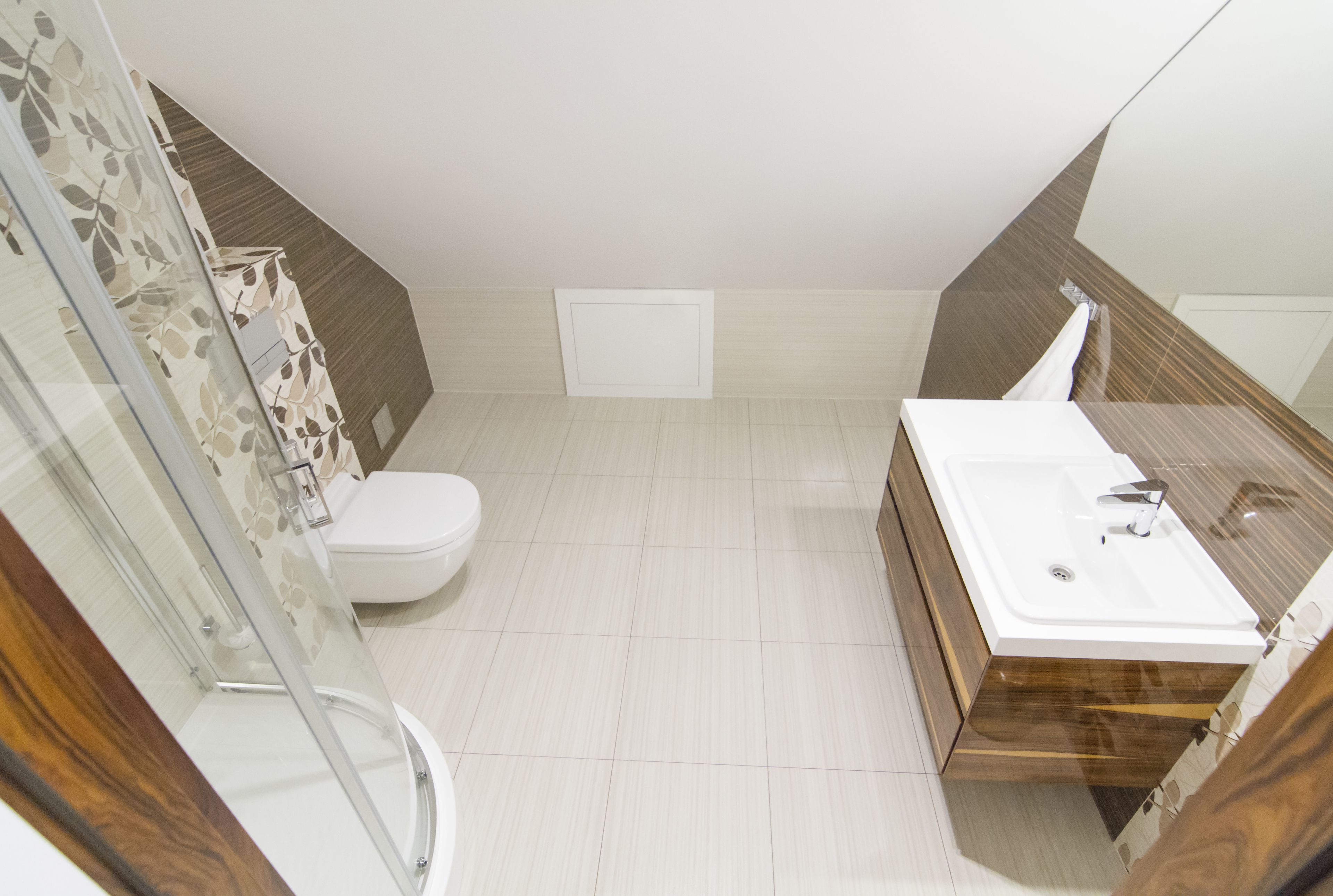 A modern bathroom with a glass shower enclosure, a white toilet, and a wooden vanity with a sink.