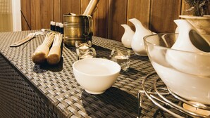 A table with various kitchenware including a bowl, a jug, and a pot, set against a wooden backdrop.