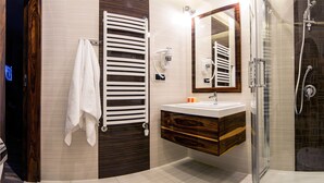 A modern bathroom with a wooden vanity, a glass shower enclosure, and a towel rack.