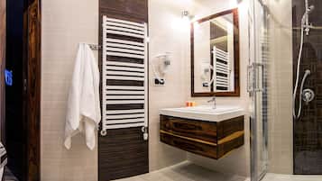 Un baño moderno con tocador de madera, cabina de ducha con vidrio y perchero.
