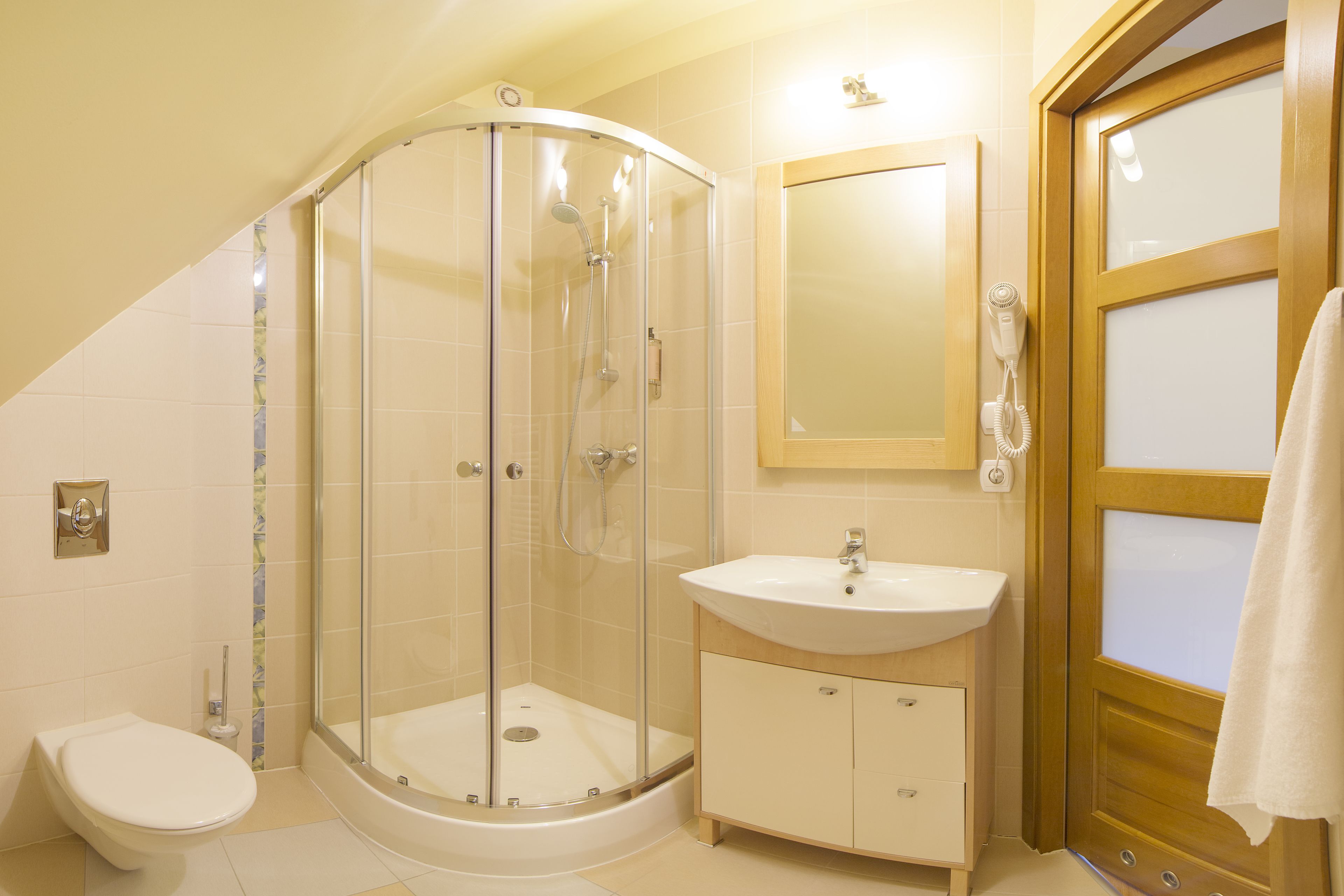 A bathroom with a glass-enclosed shower, a white sink, and a wooden door.