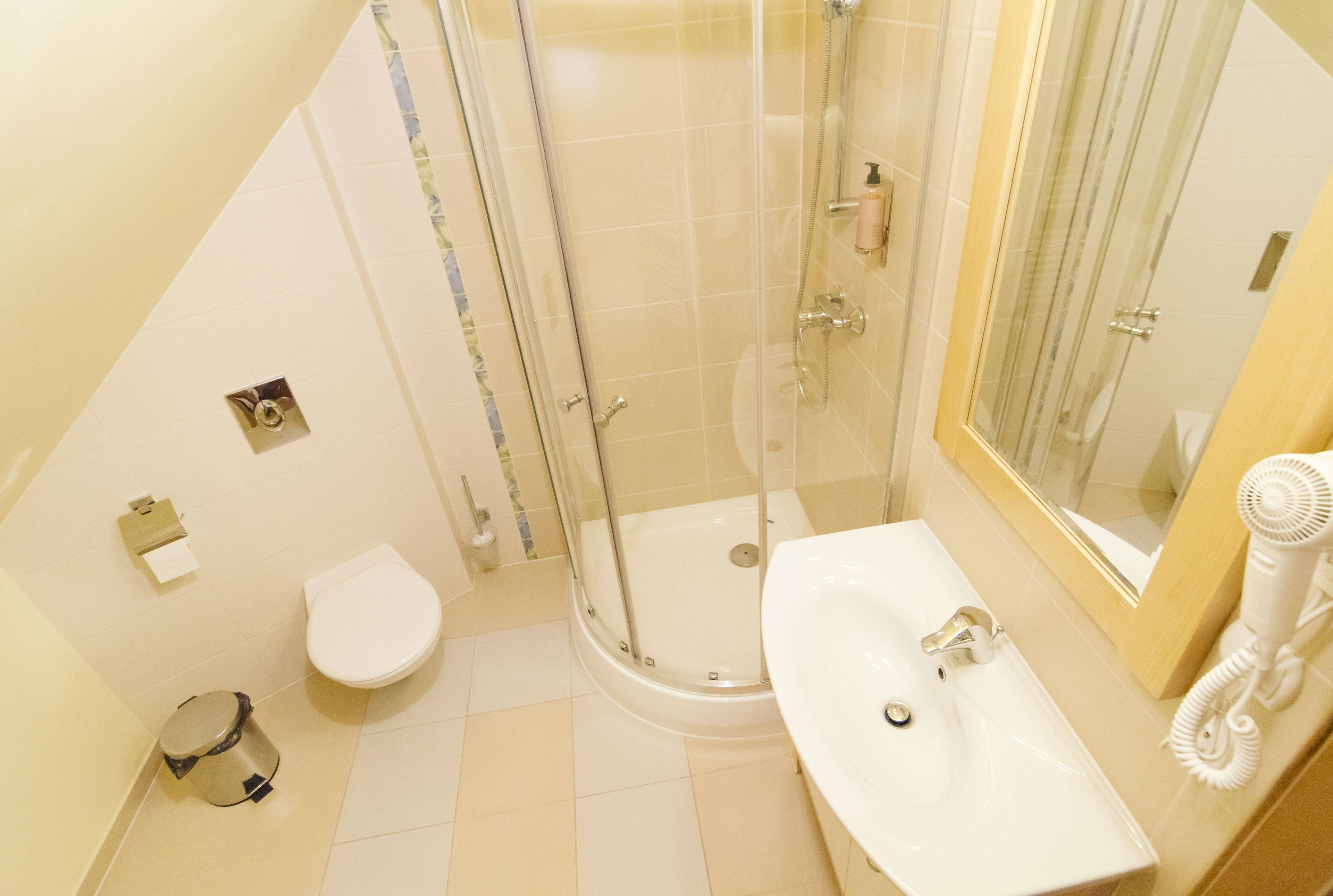 A bathroom with a toilet, sink, shower, and a mirror.