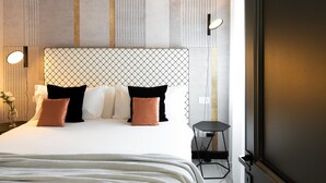 Ett modernt hotellrum med en stor säng, en takfläkt, ett sängbord och ett litet bord vid sängen.